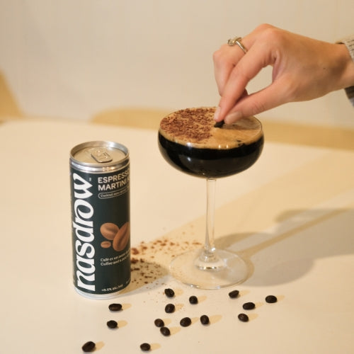 Hand garnishing a non-alcoholic Nasdrow Espresso Martini with cocoa on top of a stylish glass.
